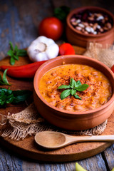 Traditional baked beans in tomato sauce cooked in retro clay pot with spices and vegetables.