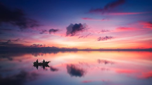 Cinemagraph of fishing on lake at sunset with pink sky and still water reflection background