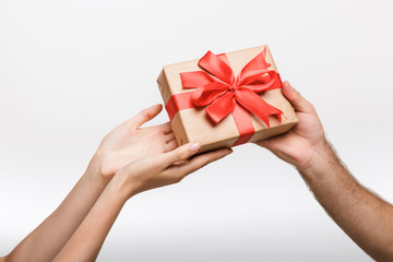 Man's and woman's hands isolated over white wall background holding present gift box.