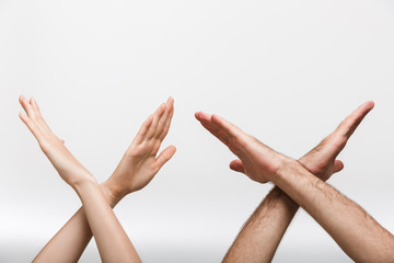 Man's and woman's hands isolated over white wall background showing stop gesture.