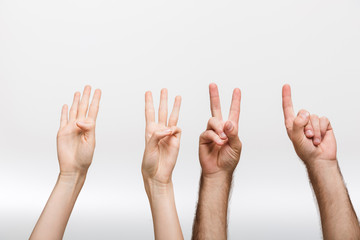 Man's and woman's hands isolated over white wall background showing counting numbers by fingers.