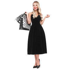 Fototapeta premium Beautiful girl with Hollywood locks, classic make-up, red lips in a black elegant dress and shopping bags. Beauty face and body.