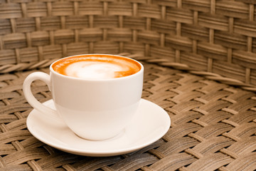 Cappuccino in white cup on wood table background at cafe. Place for text. Bewerages, coffee lovers and morning menu concept. Stylish toning.