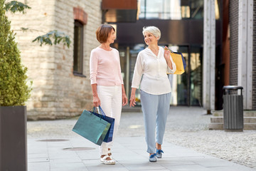 sale, consumerism and people concept - two senior women or friends with shopping bags walking along tallinn city street
