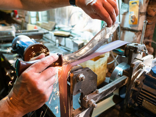 sharpening Khukur knife on grinding machine