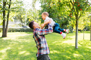 Fototapeta premium family, fatherhood and people concept - happy father with little son playing in summer park