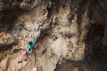 Climber overcomes challenging climbing route. A girl climbs a rock. Woman engaged in extreme sport. Extreme hobby.