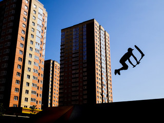 Silhouette of a young man on a scooter. Execution of the trick in the jump
