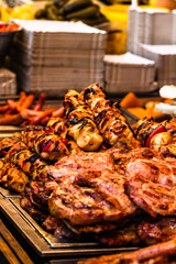 Juicy steaming meat on a charcoal grill, pork steaks, chicken breast, sausages, pieces of meat chops at a street food festival