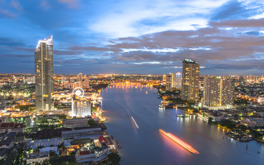 Fototapeta na wymiar Bangkok cityscape rooftop view at night over Chao Phraya River waterfront with hotel buildings in central business district (CBD) and tourist boats transportation