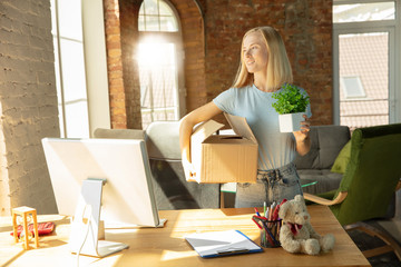 A young businesswoman moving in the office, getting new work place. Young caucasian female office worker equips new cabinet after promotion. Looks happy. Business, lifestyle, new life concept.