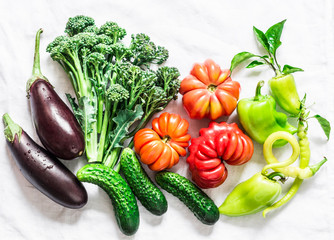 Fresh seasonal vegetables food background. Aubergines, tomatoes, peppers, broccoli on a light background, top view. Flat lay, copy space