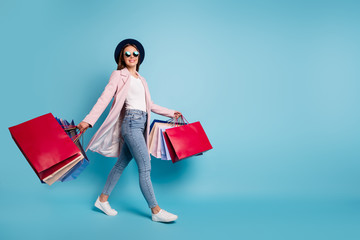 Full size photo of cute pretty cheerful lady in eyeglasses eyewear go shopping for bargains wear season cote denim jeans isolated over blue background