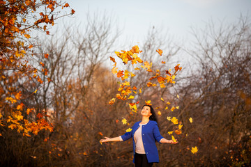 Golden autumn. Beautiful brunette caucasian woman in a blue cardigan in the city park at sunset....