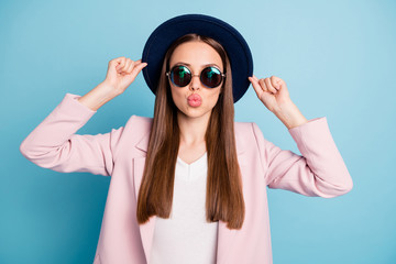 Portrait of cute lovely girl touch her hat prepare for date with her sweetheart look in mirror send air kisses wear pink season coat isolated over blue background