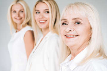 selective focus of three generation blonde women isolated on grey