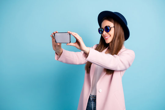 Profile side photo of cheerful girl using her cell phone making self portrait enjoying promenade wearing pink outfit isolated over blue background