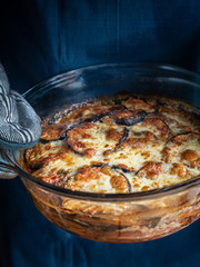 veggie lasagne, autumn mood, healthy food with orange and blue colours, hand holding the dish, serving