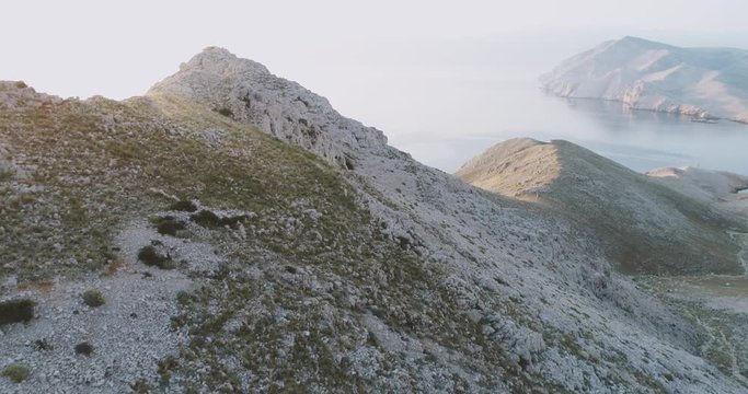 Aerial Drone flight in summer over mountains on the island krk near baska in croatia during sunrise over the sea