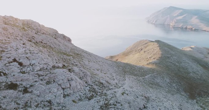Aerial Drone flight in summer over mountains on the island krk near baska in croatia during sunrise over the sea