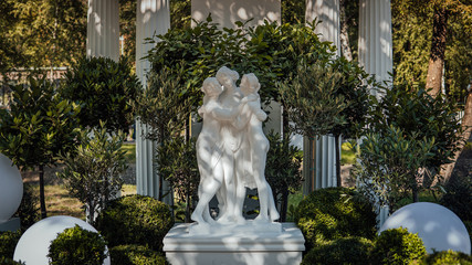 Obraz premium A beautiful white sculpture on the background of green trees in the park.