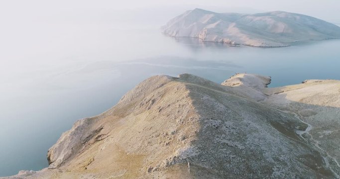 Aerial Drone flight in summer over mountains on the island krk near baska in croatia during sunrise over the sea