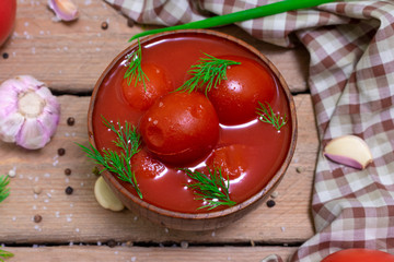 Tomatoes in their own juice in a wooden bowl with spices. Tomatoes on a wooden background. Stewed tomatoes