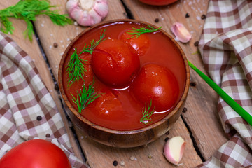 Tomatoes in their own juice in a wooden bowl with spices. Tomatoes on a wooden background. Stewed tomatoes