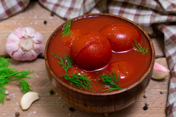 Tomatoes in their own juice in a wooden bowl with spices. Tomatoes on a wooden background. Stewed tomatoes