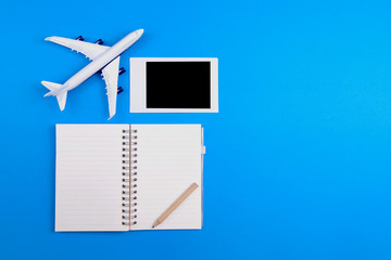 Plane model notebook  pencil and picture frame placed on a blue background Tourism and Travel Concept