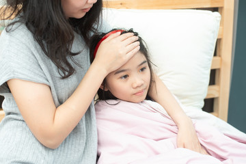 Mother checking body temperature of her daugther with her hand.