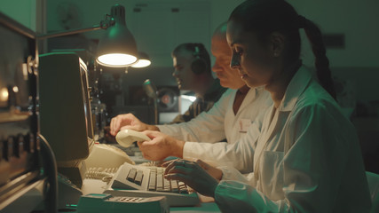 Scientists working in a vintage style control room