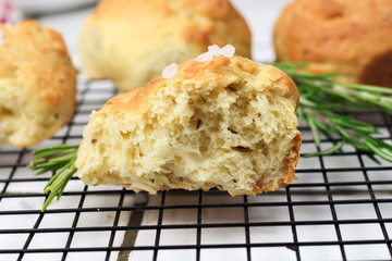 homemade fresh herb bread rolls of Provencal herbs with salt and a sprig banch of rosemary. Bread rolls bakery style on the cooling wrak