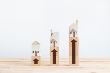 Miniature white house on wooden block with growth arrow sign in property investment concept