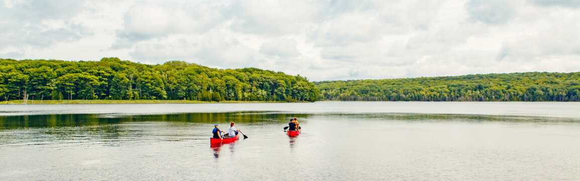 Canada forest park nature with family friends riding in red kayaks canoe boats in water. Beautiful landscape scene at Canadian  lake river area. Web banner header for website.