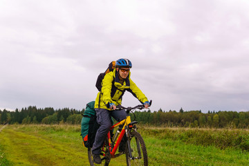 bikepacker rides on a dirt road through a field