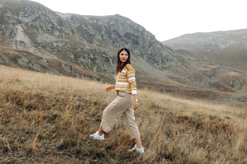Naklejka premium Hiker woman standing with hands up achieving the top. Girl welcomes a sun. Conceptual design. Successful woman hiker open arms on sunrise mountain top. Girl in long white dress in the mountains.