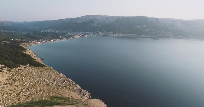 Aerial Drone flight in summer over mountains on the island krk near baska in croatia during sunrise over the sea