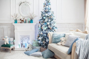 Christmas tree decorated with lovely ornaments and classical style fireplace in white room. New year scene.