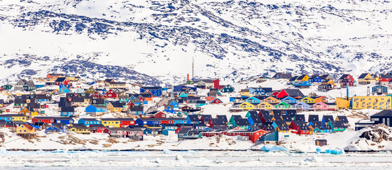 Arctic city center panorama with colorful Inuit houses on the rocky hills covered in snow with snow and mountain in the background, Ilulissat, Avannaata municipality, Greenland © vadim.nefedov