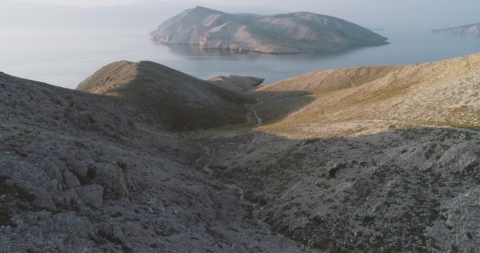 Aerial Drone flight in summer over mountains on the island krk near baska in croatia during sunrise over the sea
