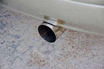 A silver bronze car exhaust parked on the side of the road