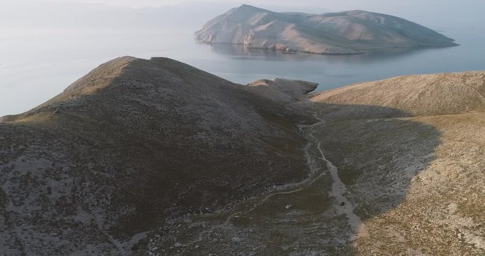Aerial Drone flight in summer over mountains on the island krk near baska in croatia during sunrise over the sea