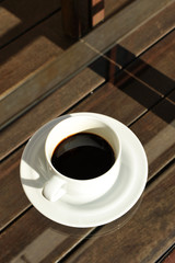 Cup of black coffee on the glass of a wooden table top view