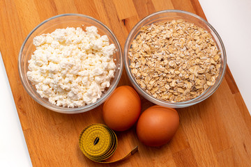 cereals, measuring tape, farm cottage cheese, egg close up on white background protein healthy diet fat free concept eco product sports nutrition