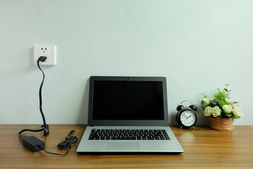 Plug in power outlet adapter cord charger on a white wall of the laptop computer on Wooden floor