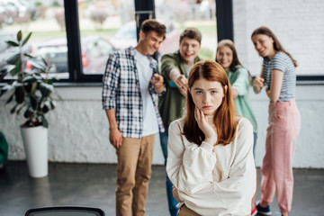selective focus of group of teenagers bullying sad girl