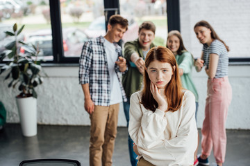 selective focus of group of teenagers bullying sad girl