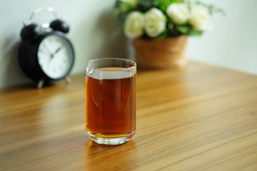 Tea in a clear glass on a wooden office desk with a laptop computer, Tea afternoon break