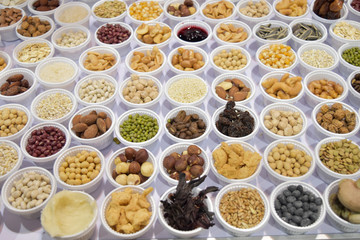 Cereal grains, seeds, beans on white plastic plate.